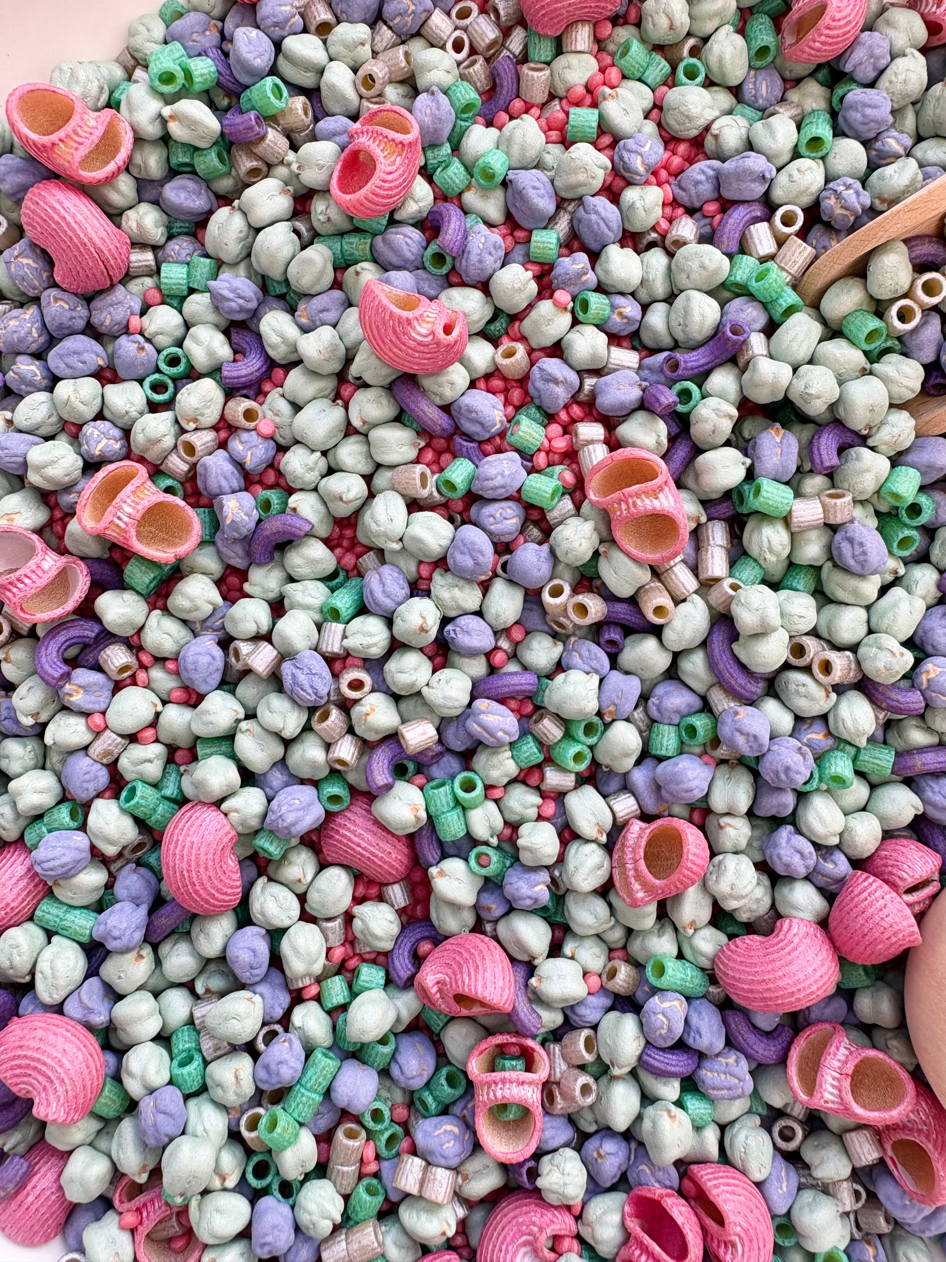 Close up of mermaid treasures, a dyed sensory bin filler made from pasta and chickpeas 