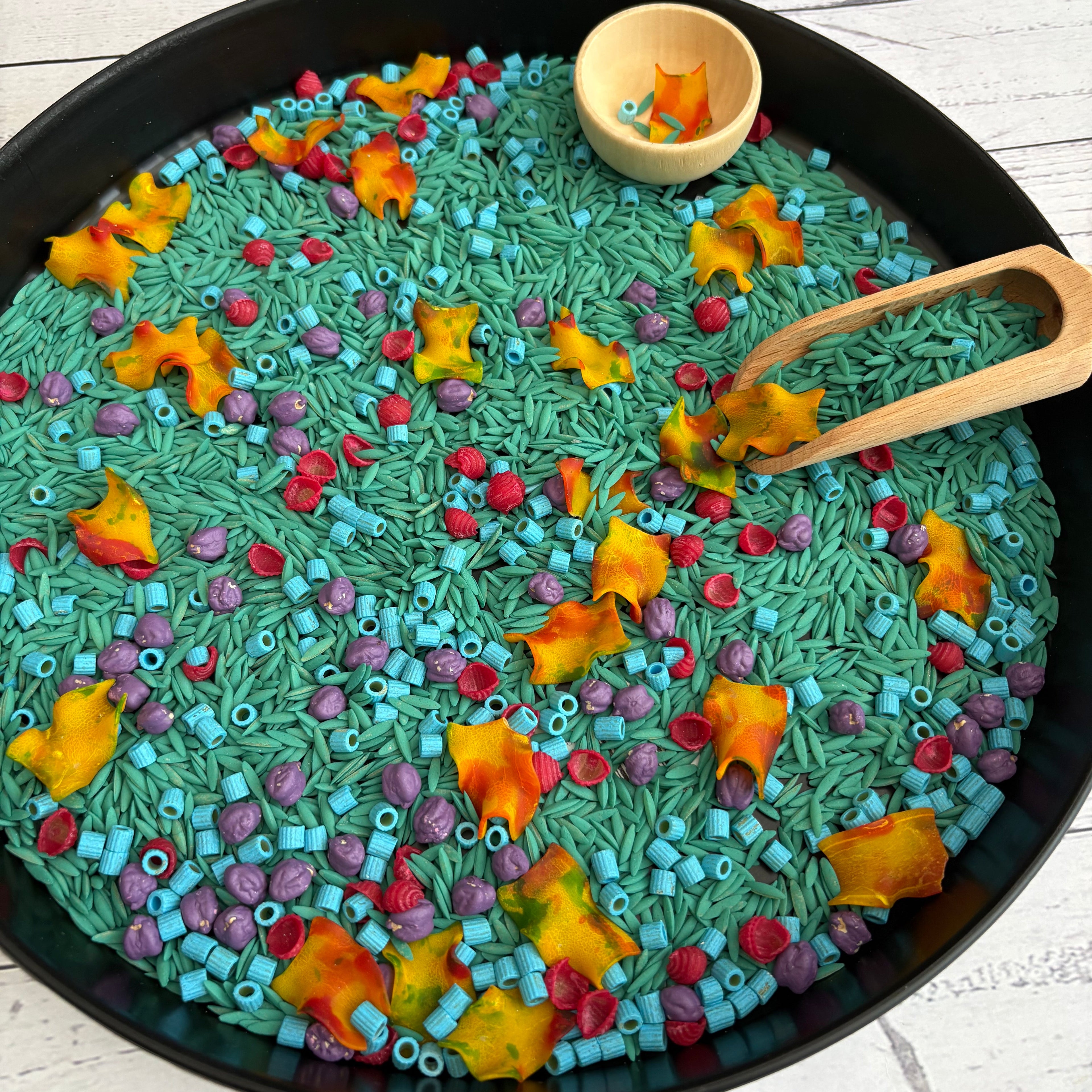 Colorful sensory bin with toys on a wooden surface
