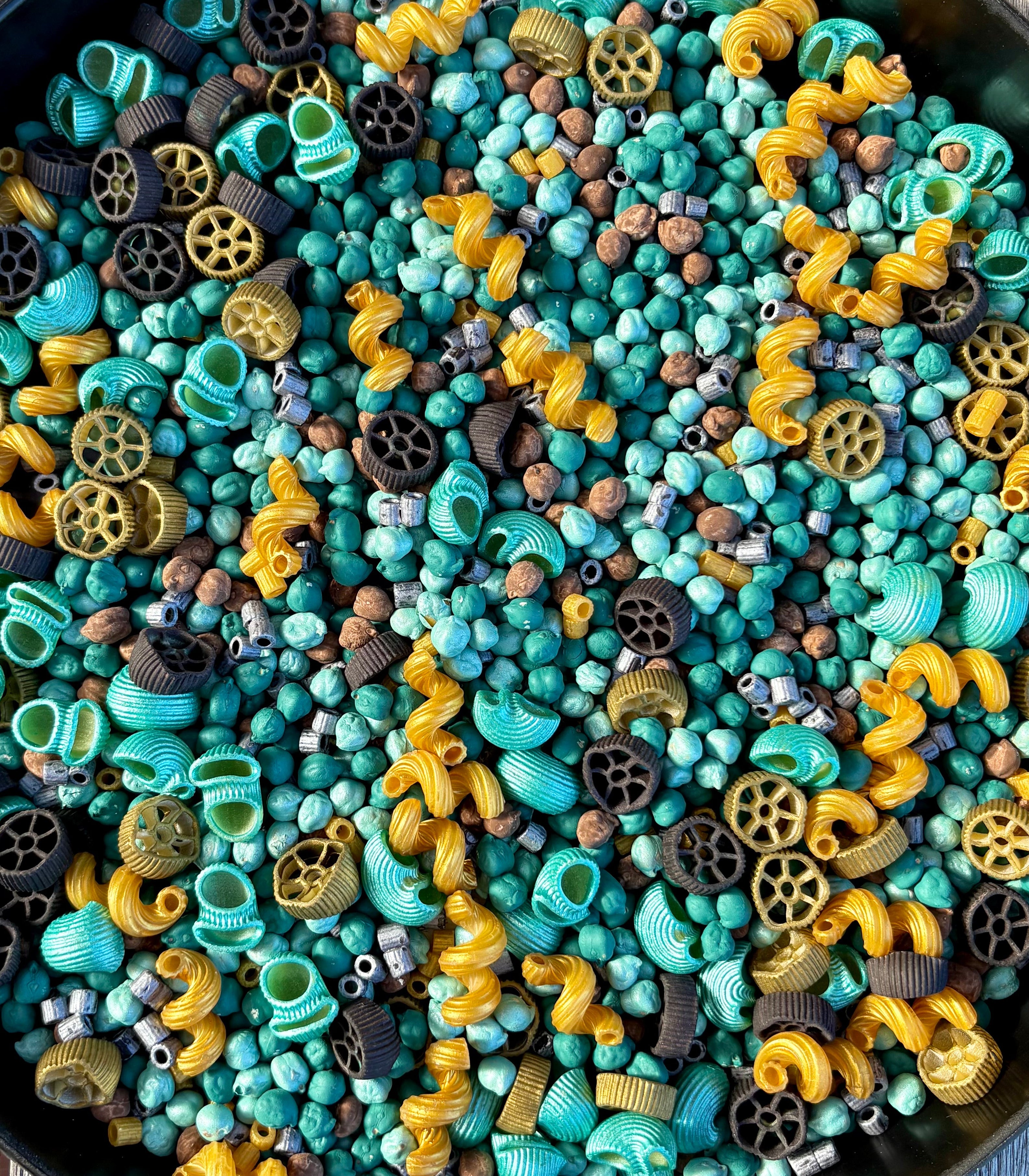 Assorted colorful pasta in a black bowl on a wooden surface